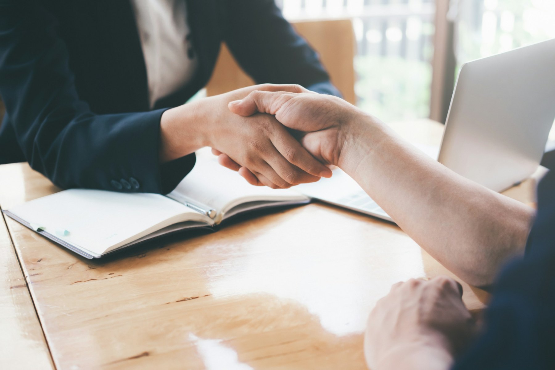 Two people shaking hands across a desk